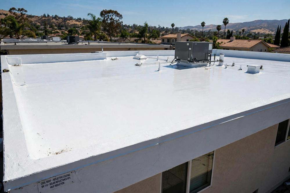 Bright white reflective cool roof coating on a flat roof in summer sun